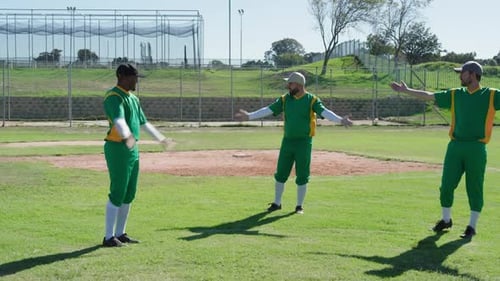 Three Men in Green Baseball Uniforms Warming Up on a Sunny Field