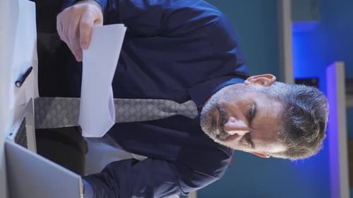 Man Examines Documents at Desk in Modern Office