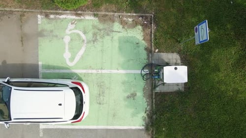 White car slowly approach an EV charging station for electric vehicle powered by green energy,