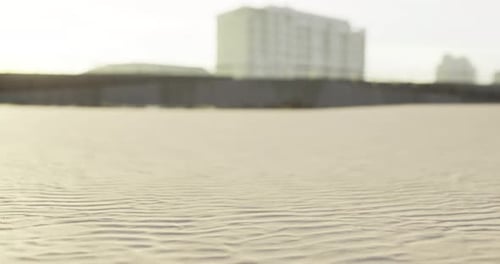 Sand Formations Stretch Across the Beach Near a Modern Building at Sunset