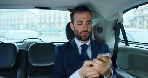 Man in Suit Using Smartphone in Car