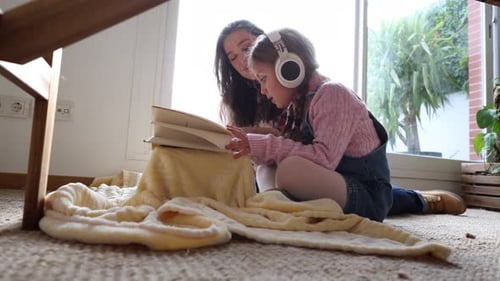 Girl and Woman Reading Book on Floor Together