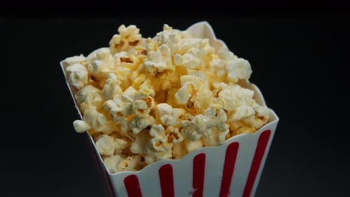 Rotation von Air Popcorn in einer klassischen Box auf schwarzem Hintergrund, Nahaufnahme