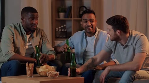 Friends Toasting with Beer and Eating Snacks Indoors