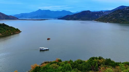 Approaching the boats moving by the calm waterscape surrounded by the mountains.