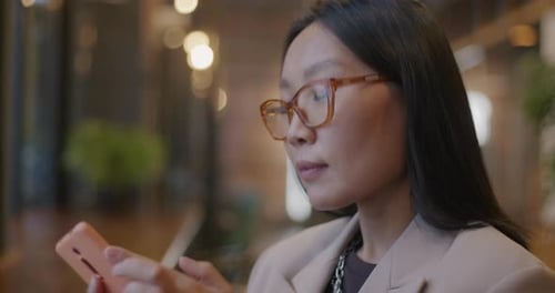 Young Asian Entrepreneur Making Mobile Phone Call Speaking to Client Discussing Work Indoors in Cafe