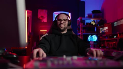 Smiling Gamer with Headphones in Neon Lit Room