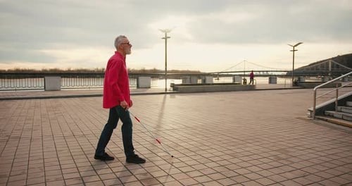 Senior Blind Man with White Cane Walking Across the Street in City