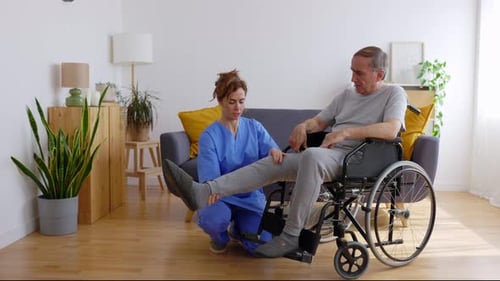 Medical Professional Assists Senior with Leg Exercise