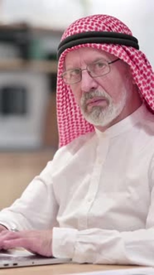 Senior Man in Traditional Headwear Working on Laptop