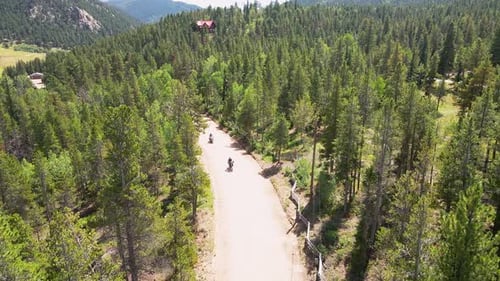 Two motorcycle riders drive towards the camera with an aerial view dolly backwards in the mountains.