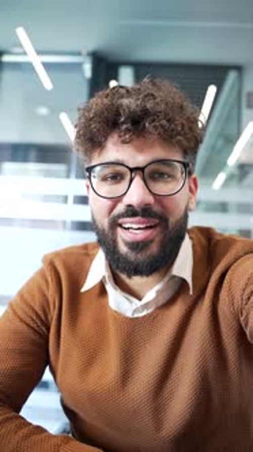 POV Vertical. Smiling businessman talking on video call using a phone in the office. Confident male