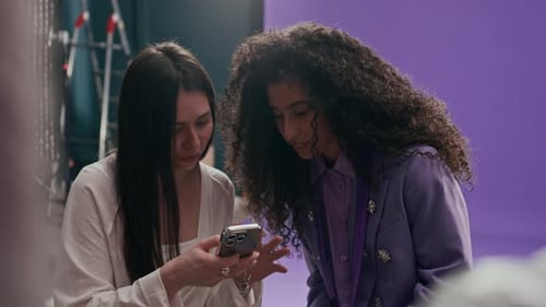 Production Assistant Sharing Content on Phone with Female Model in Photo Studio