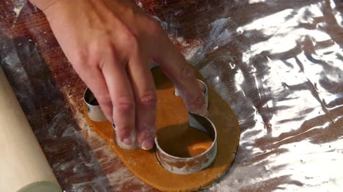 Cutting Gingerbread Man Cookie on Floured Wooden Table