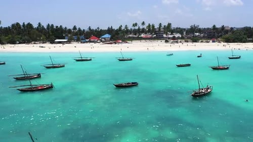 Vibrant wooden boats float peacefully in crystal-clear turquoise waters under a bright sky.