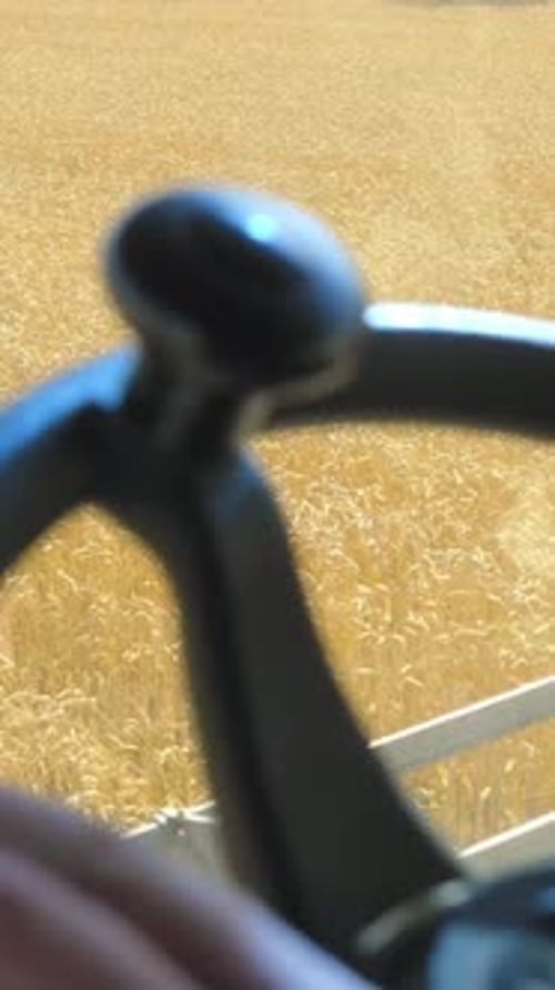 Vista aproximada da mão do fazendeiro no volante de máquinas agrícolas no campo de trigo dourado