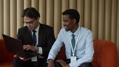 Businessmen Discussing Data on Laptop in Modern Setting