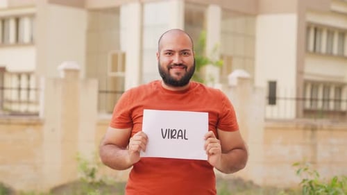 Young Adult Smiling Holding a Viral Sign