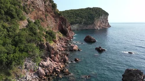 Camera Panning Showing Beautiful Turquoise Water Meeting Rocky Coastline Aerial View