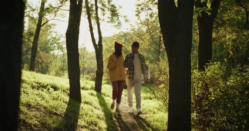 Couple Walking Through Forest, Sipping Coffee