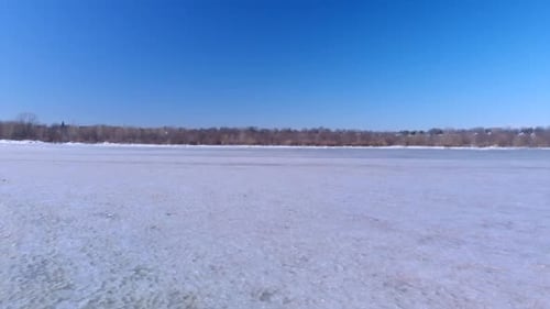 drone flight over large pile of fragments of ice and frozen river to a forest on the other side.