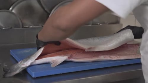 Close-Up Shot of a Chef Filleting and Flipping over a Fresh Salmon Fish