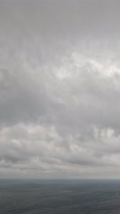 Timelapse Nuages de nimbostratus pluvieux se déplaçant dans un ciel lumineux au coucher du soleil au-dessus d'une mer orageuse, vue aérienne abstraite
