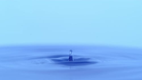 Water Drop Impacts Blue Liquid Creating Ripples