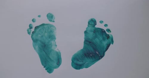 Meticulous human footprints artfully crafted with green paint on grey surface