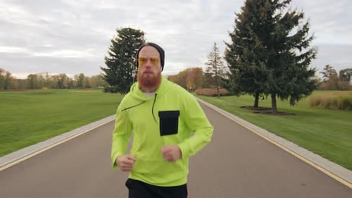 Homem barbudo ruivo confiante correndo ao longo da ciclovia no seio da natureza