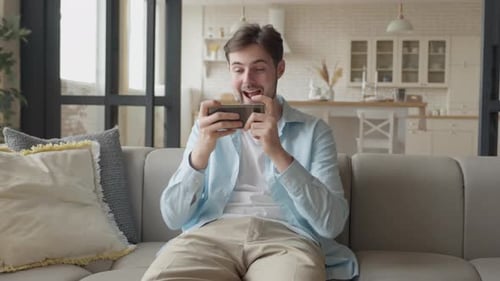 Man Plays Mobile Game on Phone at Home