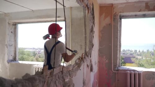 Un contratista destruye una pared con un mazo haciendo un agujero para reorganizarlo