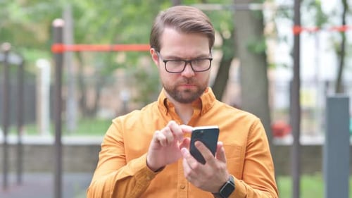 Portrait of Young Man Text Messaging on Phone Outdoor