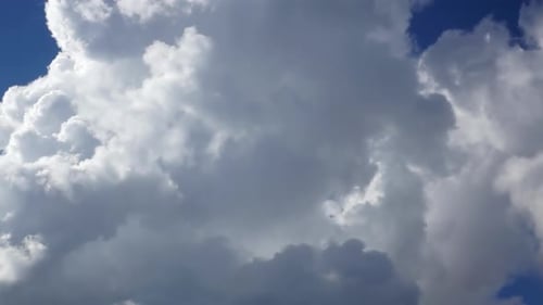 Fluffy White Clouds Float Across a Blue Sky