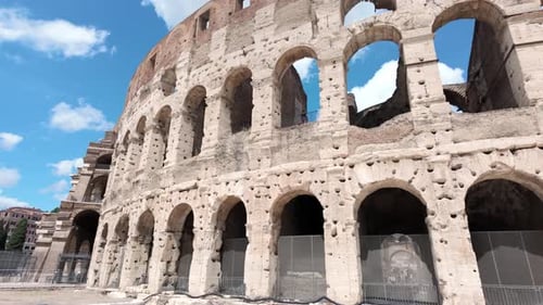 Clouds and blue sky seen through arches of historical Colosseum in Rome