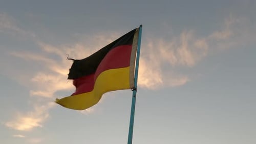 Weathered German Flag Waving Proudly Against Soft Sunset Sky
