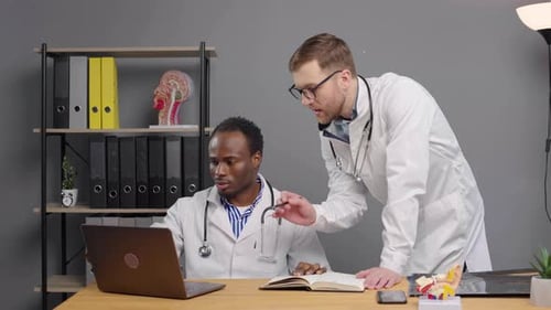 Two Doctors Reviewing Laptop Screen at Clinic