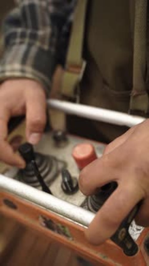 Vertical video of worker hands operating industrial joystick control panel on construction site