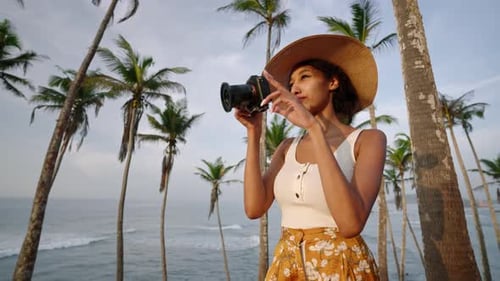 Une femme afro-américaine prend des photos avec un appareil photo sur une île tropicale Une photographe multiraciale