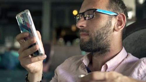 Young Man Texting on Smartphone and Drinking Beverage in Cafe 30s