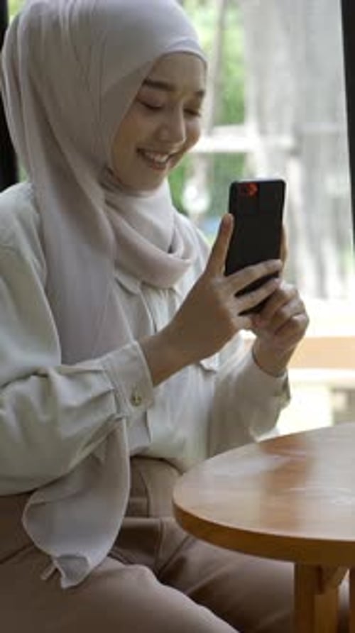 An upwardly mobile Asian Muslim woman enjoying a relaxing moment in the coffee shop on a bright sunn