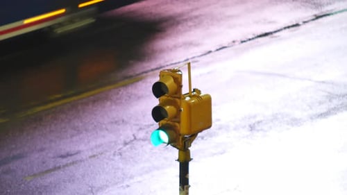 Close-up de um semáforo com luz verde acesa. Luzes de velocidade borradas dos carros que passam. Semáforos