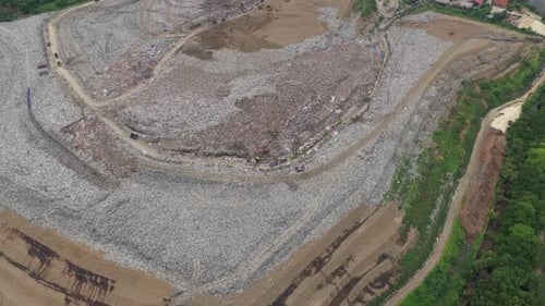High aerial view showing a massive garbage dump with piles of plastic waste and trash, highlighting