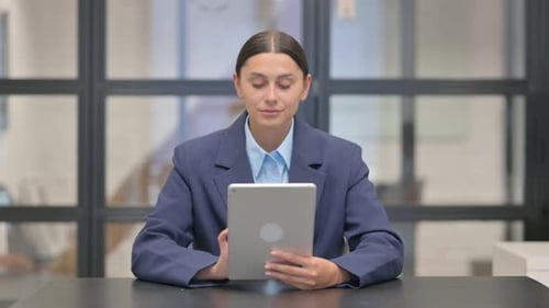 Young Adult Woman Works on Tablet in Office