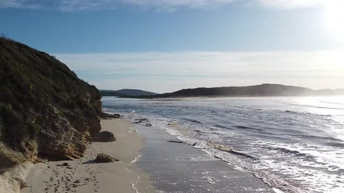 Scenic Coastal Beach with Rolling Waves and Rugged Cliffs