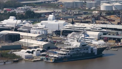 Grand yacht de luxe en construction dans un chantier naval avec grues, assemblage de navires