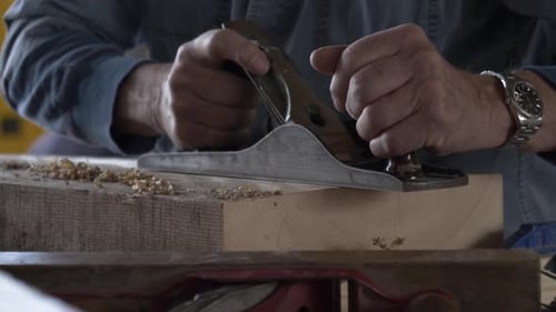 Woodworker Using Hand Plane on Wood Plank