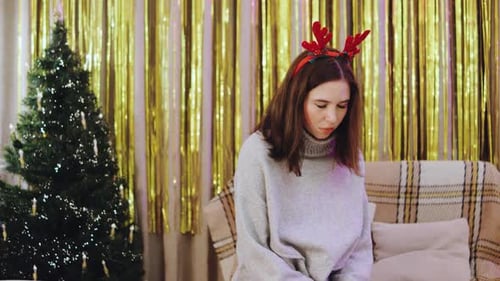 A Distressed Young Woman Sheds Tears in a Christmasthemed Room The Festive Decorations Tree and
