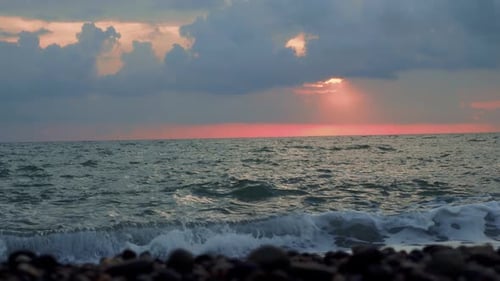 Waves rolling onto rocky beach of the black sea during the sunset, slow motion