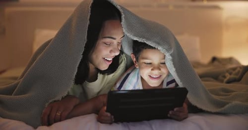 Mother and Child Watching Tablet Under Blanket at Night